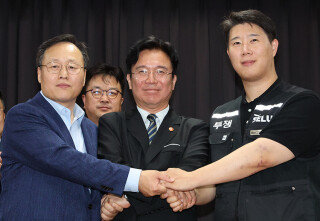 5월 20일 경기 수원시 장안구 경기고용노동청에서 열린 삼성전자 임금협상에서 여명구 DS 부분 피플팀장, 김영훈 고용노동부 장관, 최승호 초기업노조 삼성전자지부 위원장(왼쪽부터)이 잠정 합의안에 서명한 뒤 손을 맞잡고 있다. 사진공동취재단