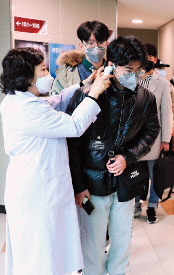 한국교통대는 3월 13일 기숙사에 머물던 중국인 유학생 전원을 격리 해제했다. 이날 기숙사를 나서는 중국인 유학생들이 발열 검사를 받고 있다. [뉴시스]