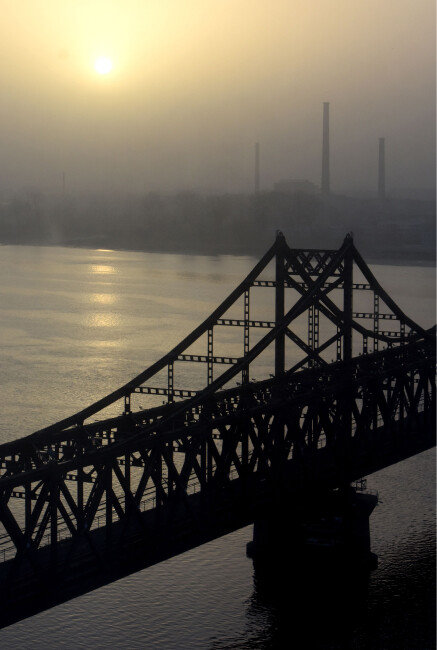 2016년 3월 6일 중국 단둥시 인근에서 바라본 압록강대교와 북한 신의주 공장 위로 태양이 떠오르고 있다. [뉴시스]