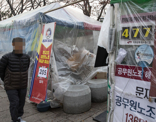 진보단체(‘전국교원노조’와 ‘공무원노조’)의 농성 천막 앞으로 ‘전교조 법외노조 직권취소 노숙 205일차’라는 문구가 보인다.