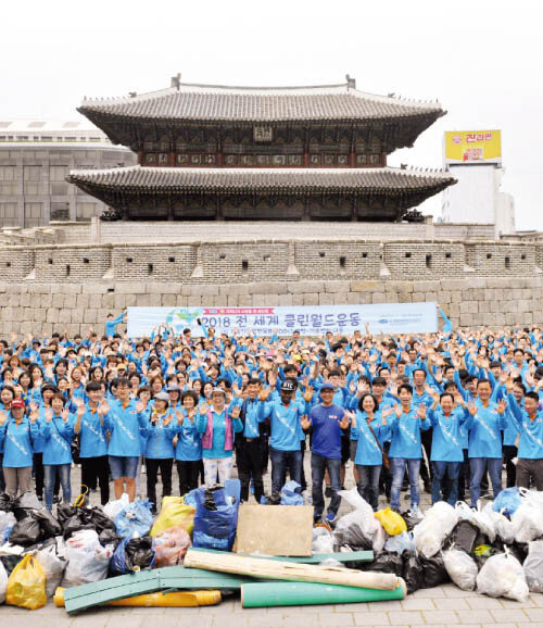 위러브유 회원들이 서울 종로구에서 개최한 클린월드운동을 마치고 환하게 웃고 있다. 그 뒤로 서울의 랜드마크인 흥인지문이 보인다.