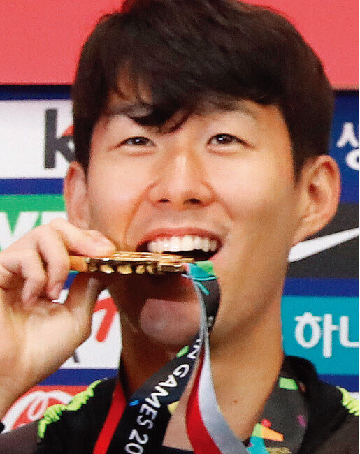 9월 3일 오전 인천국제공항을 통해 입국한 남자 축구대표팀 주장 손흥민이 금메달을 깨물며 포즈를 취하고 있다. [뉴스1]
