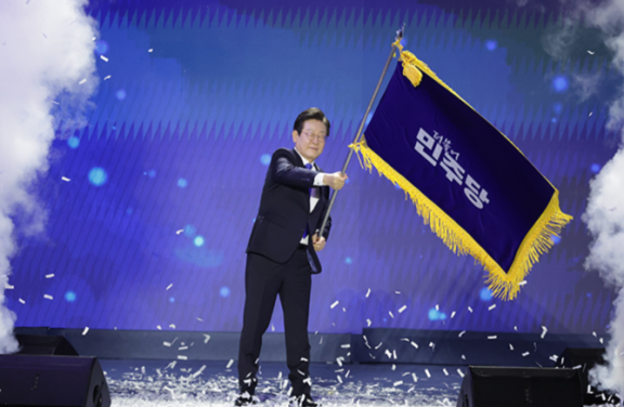 이재명 대통령이 지난해 8월 18일 서울 송파구 올림픽체조경기장에서 열린 더불어민주당 전당대회에서 당 대표 연임에 성공한 뒤 당기를 흔들고 있다. 동아DB