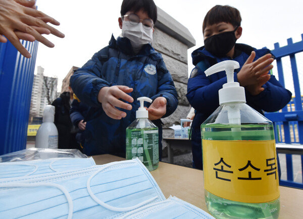 지난 1월 말, 경기 수원시 한 초등학교 학생들이 교문 앞에서 손소독제를 바르고 있다. [뉴시스]