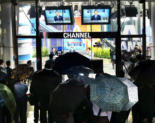 2014년 5월 11일 서울 청계천로 동아미디어센터 오픈스튜디오에서 진행된 모정당 서울시장 경선 후보 TV토론회를 시민들이 우산을 받쳐든 채 지켜보고 있다,[양회성 동아일보 기자]