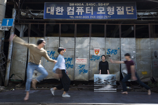 철공소를 배경으로 즉석 연기를 펼치고 있는 예술가들.