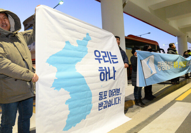 북한 선수단 본진 32명이 2월 1일 양양공항에 도착한 가운데 환영 나온 6·15 남측위원회 회원들이 플래카드를 들어 보이고 있다. 
