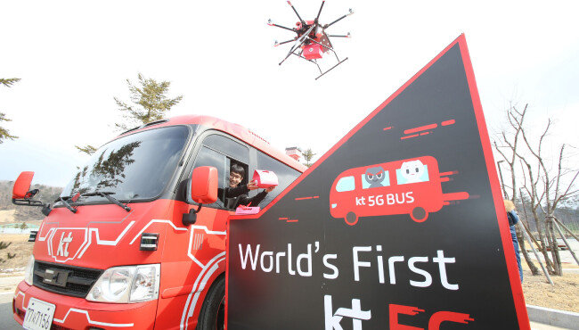 KT가 평창 동계올림픽 기간 중 선보인 ‘자율주행 5G 버스’. 평창군 알펜시아 리조트에서 KT 관계자가 5G 버스 안에서 자율주행 드론으로 배달된 택배를 받는 시연을 하고 있다. [뉴시스]