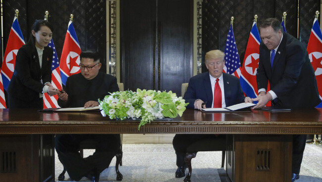 6월 12일 김정은 북한 국무위원장과 트럼프 미 대통령이 공동성명에 서명하고 있다. 이에 보수정당인 자유한국당은 트럼프를 비난했다. [AP 뉴시스]