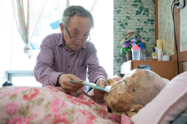 손수 만든 죽을 어머니에게 먹이고 있는 정성기 씨. [지호영 기자]