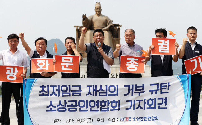 최승재 소상공인연합회 회장(왼쪽 네 번째)과 회원들이 8월 3일 서울 종로구 광화문광장에서 열린 최저임금 재심의 거부 규탄 기자회견에서 구호를 외치고 있다. 소상공인연합회는 이 자리에서 “소상공인들의 분노를 모아 오는 8월 29일 ‘전국 소상공인 총궐기’에 나서는 등 직접 행동에 돌입하겠다”고 밝혔다. [뉴스1]