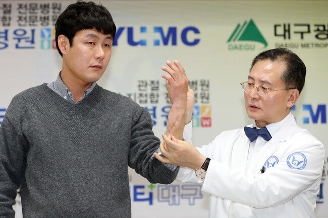 국내 최초 팔이식 수술 1주년을 기념해 2월 2일 대구 W병원에서 열린 경과 설명회 현장. 우상현 원장(오른쪽)이 손진욱 씨의 팔과 손 상태를 살펴보고 있다. [뉴스1]