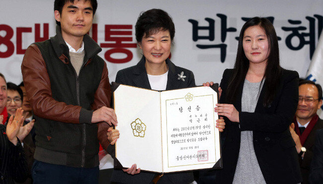 2012년 12월 20일. 박근혜 제18대 대통령 당선자가 서울 여의도 새누리당사에서 열린 중앙선거대책위원회 해단식에 참석해 중앙선거관리위원회로부터 교부받은 당선증을 대학생 대표들과 함께 든 채 활짝 웃고 있다. [동아DB]