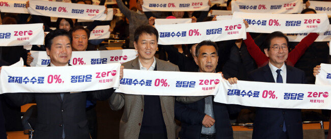 박원순(오른쪽) 서울시장과 소상공인들이 지난해 12월 20일 서울 중구 대한상공회의소 국제회의장에서 열린 제로페이 이용 확산 결의대회에서 ‘결제 수수료 0%, 정답은 제로페이’ 펼침막을 들고 있다. [뉴시스]