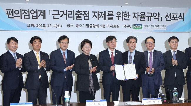 김상조 공정거래위원장(왼쪽에서 다섯 번째)이 2018년 12월 4일 서울 여의도 중소기업중앙회에서 열린 편의점업계 ‘근거리출점 자제를 위한 자율규약’ 선포식에서 편의점업계 대표들과 기념촬영을 하고 있다. 