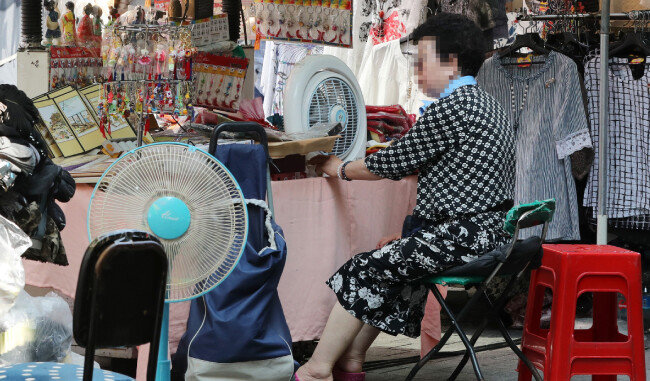 지난해 여름 서울 남대문시장에서 한 상인이 선풍기로 더위를 식히는 모습. [뉴스1]