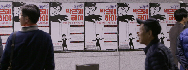 2016년 11월 12일 오후 서울 세종로 일대에 나붙은 포스터 앞을 행인들이 지나고 있다. [박해윤 기자]
