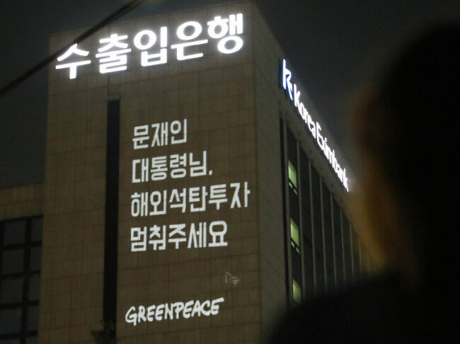 6월 30일 오후 서울 영등포구 여의도 공원 인근에서 국제환경단체 그린피스 관계자들이 정부의 해외 석탄 투자 중단 촉구 메시지를 담은 레이저 빔을 한국수출입은행 건물에 투사하고 있다. [뉴시스]
