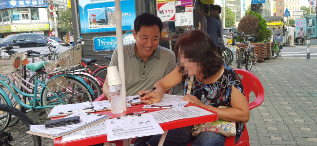 오세훈 전 서울시장이 서울 광진구 거리에서 한국당 당원 모집 활동을 하고 있다. 한 시민이 오 전 시장의 권유로 입
당원서를 쓰는 모습.