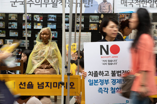 일본군 위안부 피해자를 기리는 평화의 소녀상 앞에서 한 시민이 ‘보이콧’ 재팬 피켓을 들고 있다.