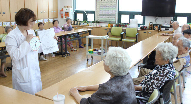 서울 마포구 창전데이케어센터에서 작업치료사가 치매 환자들에게 종이 시계를 만드는 방법을 설명하고 있다. [창전데이케어센터 제공]