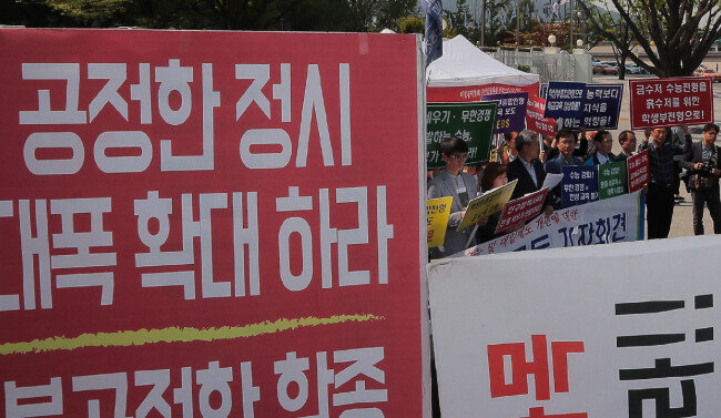 학생부종합전형 확대를 요구하는 교육단체와 정시 확대를 요구하는 단체가 2018년 4월 25일 서울 종로구 세종로 정부서울청사 정문에서 서로 마주 보며 피켓을 들고 있다. [원대연 동아일보 기자]