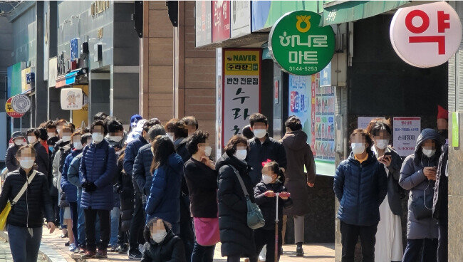 3월 14일 서울 마포구의 한 약국 앞에 평일에 마스크를 사지 못한 시민들이 줄지어 서 있다. [뉴스1]