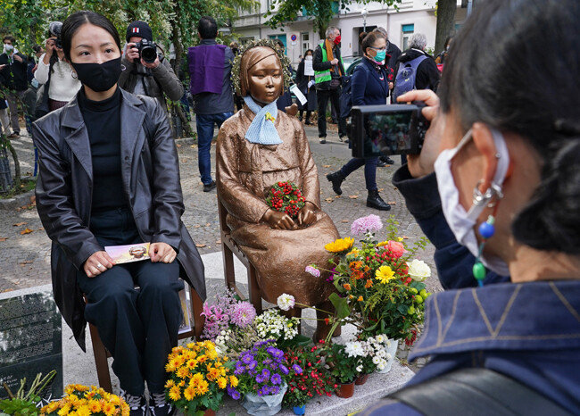 한 시민이 소녀상 옆 자리에 앉아 사진을 찍고 있다. [GettyImage]
