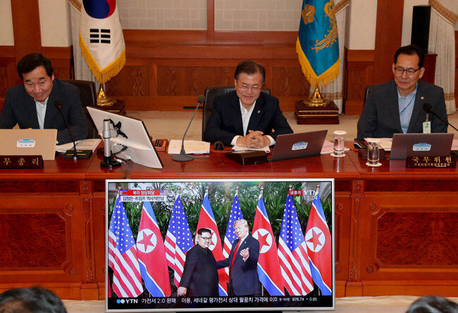 문재인 대통령이 2018년 6월 12일 청와대 세종실에서 국무회의를 시작하기에 앞서 싱가포르 북-미 정상회담에서 김정은 북한 국무위원장과 도널드 트럼프 미국 대통령이 만나는 장면의 생중계 화면을 지켜보고 있다. [청와대 사진기자단]