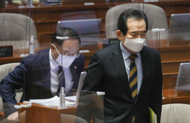 정세균 국무총리(오른쪽)가 2월 5일 국회 본회의장에서 열린 대정부 질문에서 의원들의 질의에 답변하기 위해 이동하고 있다. 여당 의원들은 4차 재난지원금 등과 관련해 홍남기 경제부총리 겸 기획재정부 장관(왼쪽)을 계속 압박했다. [사진공동취재단]