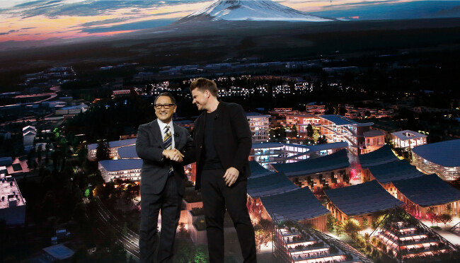 도요다 아키오 도요타 사장(왼쪽)과 비야케 잉겔스 건축가가 지난해 1월 6일 미국 라스베이거스에서 열린 ‘CES 2020’에서 ‘우븐시티’ 계획을 발표하며 악수하고 있다. [AP=뉴시스]