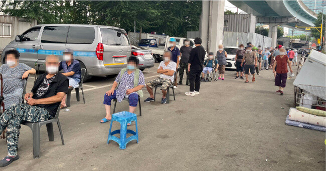  7월 29일 서울 영등포구 영등포역 고가차도 아래에 쪽방촌 주민들이 레토르트 식품·쌀·커피 등 후원 물품을 받기 위해 줄을 서 있다. 영등포 쪽방촌 주민들은 폭염을 피하고자 영등포역 고가차도 아래 그늘이 있는 곳에 모인다. [문영훈 기자]