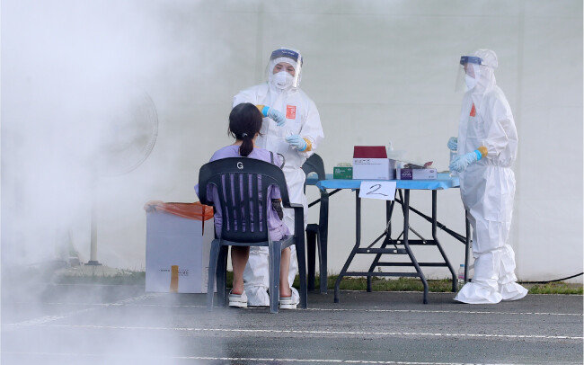 8월 5일 폭염이 발생한 대구시의 한 코로나19 임시선별검사소 풍경. 열기를 식히고자 살수차가 물을 뿌리는 가운데 의료진이 코로나19 진단검사를 실시하고 있다. [뉴스1]