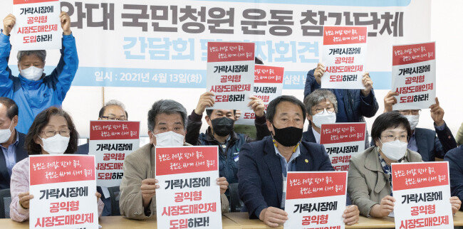 전국농민회총연맹 회원들이 4월 13일 가락시장 ‘공익형 시장도매인제도 도입’을 위한 청와대 국민청원 운동 참가단체 기자회견에서 손 피켓을 들고 있다. [뉴스1]