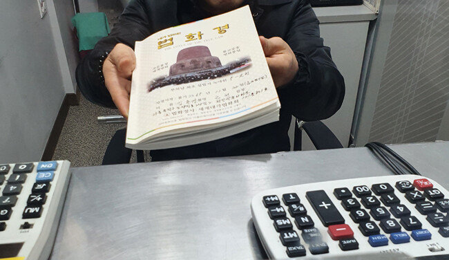 명동에서 환전소를 운영하는 김모 씨는 “오미크론 변이가 퍼지며 관광객이 돌아오리라는 희망마저 꺾어버렸다”고 울먹였다. 그가 마음을 다스리기 위해 필사하고 있다며 기자에게 보여준 법화경. [오홍석 기자]
