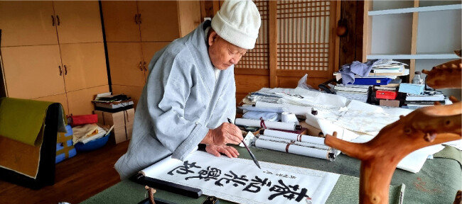 성파스님이 경남 양산 통도사 서운암 인근 산중 작업실에서 휘호를 쓰고 있다. 한국 수묵화 거장 소산 박대성 화백은 성파스님 글씨를 ‘성파체’로 칭하며 “스님은 마음과 붓과 종이가 하나 되는 경지를 아는 당대 최고 수준의 서예가”라고 평했다. [오명철 제공]