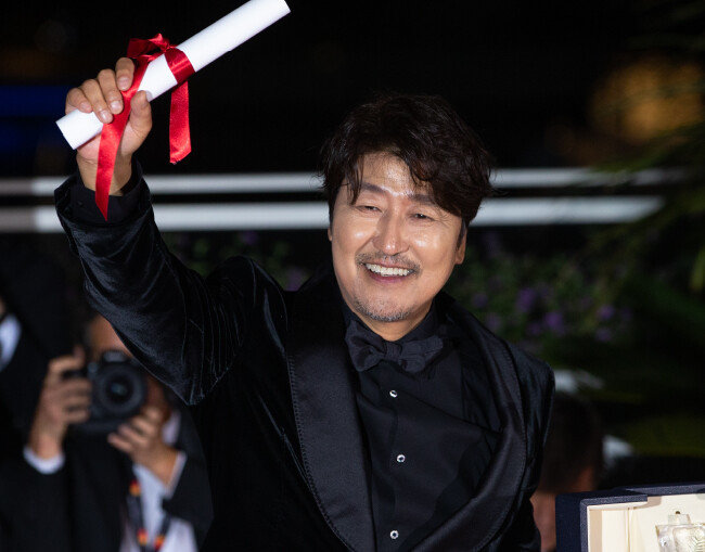 배우 송강호가 5월 28일 제75회 칸 국제영화제가 열린 프랑스 남부 칸 ‘팔레 데 페스티벌’에서 열린 폐막식에 참석해 수상한 남우주연상 트로피를 들어 보이고 있다. [뉴스1]