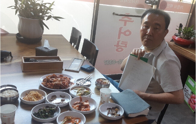이산 씨의 노트를 자랑하는 최병욱(62) 씨. 이씨가 사진 촬영을 부담스러워하자 최씨는 “부끄러울 것도 많다”며 노트를 뺏어 들고 카메라를 응시하며 “나는 사진 찍히는 거 좋아해”라고 했다. [이주홍]