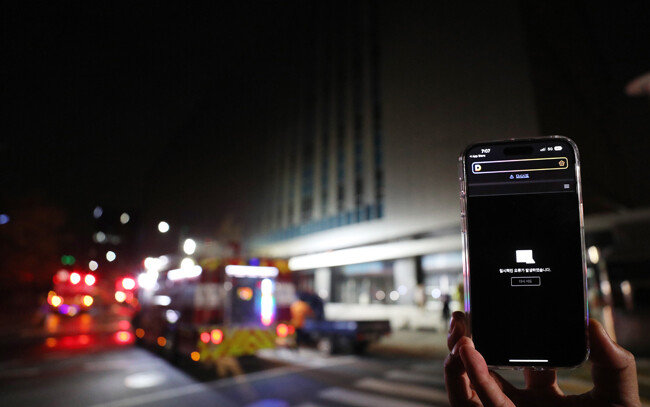 10월 15일 오후 경기 성남시 분당구 SK C&C 판교캠퍼스에서 불이 나 소방대원들이 현장을 살피고 있다. 이날 오후 카카오 등 데이터 관리 시설이 입주해 있는 이 건물 지하에서 화재가 발생하면서 카카오톡, 카카오택시 등 일부 서비스에 장애가 빚어졌다. 한 휴대전화에 다음 홈페이지 오류 안내가 뜨고 있다. [뉴스1]