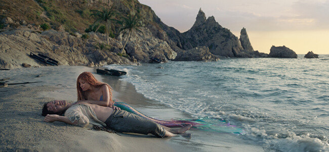 동명의 디즈니 애니메이션을 실사화한 영화 ‘인어공주’에서 에리얼(핼리 베일리)이 조난 당한 에릭 왕자(조나 하워킹)를 구출해 모래사장에 눕히고 있는 모습. [월트디즈니컴퍼니코리아]