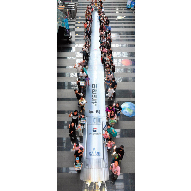 누리호가 발사된 5월 25일 광주 북구 국립광주과학관 실내 바닥에 그려진 누리호 축소 모형 그림을 배경으로 관람객들이 기념촬영을 하고 있다. [뉴시스]