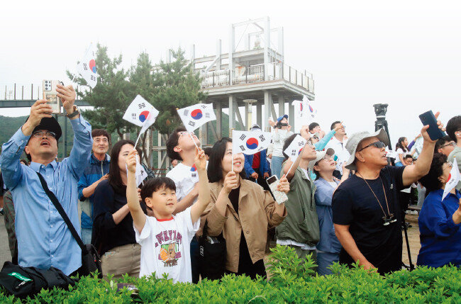 누리호가 5월 25일 오후 6시 24분, 나로우주센터에서 발사되자 전남 고흥군 우주발사전망대에 모여든 관람객들이 태극기를 들고 환호하고 있다. [뉴스1]