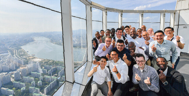 롯데월드타워 서울스카이 전망대에 오른 청년들이 한국의 발전상을 확인했다. 창문 너머로 서울 도심과 한강이 보인다.