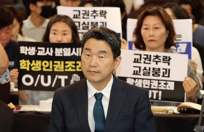 이주호 사회부총리 겸 교육부 장관이 8월 10일 서울 중구 코리아나호텔에서 열린 교권회복 및 보호를 위한 교육부-국가교육위원회 공동주최 토론회에 참석해 자리하고 있다. 이 부총리 뒤로 서울교육사랑학부모연합 학부모들이 학생인권조례 폐지를 촉구하는 손팻말을 들고 있다. [뉴스1]