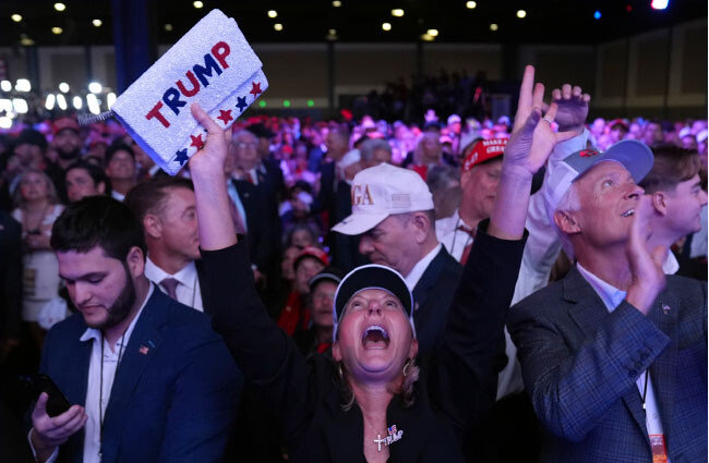 2024년 11월 5일 미국 플로리다주 웨스트팜비치의 팜비치 컨벤션센터에서 개표 결과를 지켜보던 공화당 지지자가 도널드 트럼프 미 대통령 당선인의 이름이 적힌 파우치를 들고 두 손을 치켜든 채 환호하고 있다. AP뉴시스