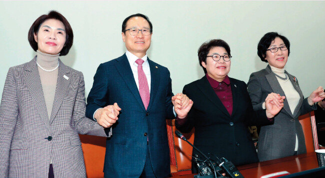 더불어민주당 소속 홍영표 국회 환경노동위원장(왼쪽에서 두 번째)이 2월 27일 법정 노동시간을 주 52시간으로 단축하는 근로기준법 개정안 처리 과정을 설명하는 기자회견을 가진 뒤 여야 간사들과 손을 맞잡고 있다. 왼쪽부터 더블어민주당 한정애 의원, 홍 위원장, 자유한국당 임이자 의원, 바른미래당 김삼화 의원.