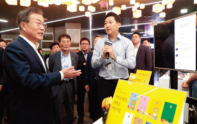 문재인 대통령이 8월 7일 서울 중구 서울시청 시민청에서 열린 인터넷전문은행 규제혁신 현장 방문 행사에서 카카오뱅크 부스를 찾아 모바일로 받는 대출 시연을 보며 설명을 듣고 있다. [뉴스1]