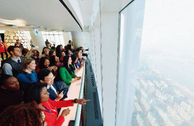 하나님의 교회 제73차 해외성도방문단이 롯데월드타워 서울스카이 전망대에서 한국인 가이드의 설명을 들으며 서울 전경을 구경하고 있다. 