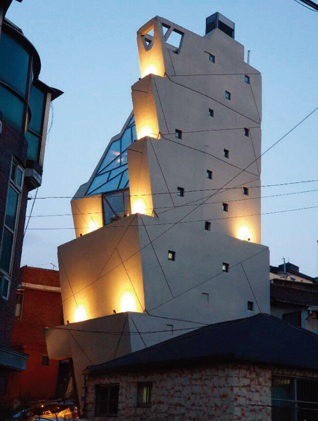 쿠엔즈버킷 도심공장 및 플래그숍의 야경. 위는 넓고 아래는 좁은 버킷(들통) 다섯 개가 층층이 쌓여 있는 형상을 확인할 수 있다. [사진 제공·변용한]