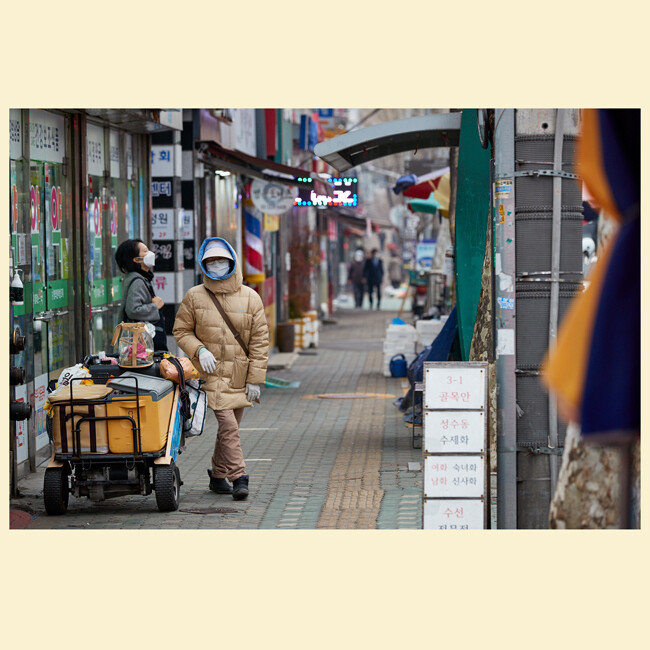 야쿠르트 아주머니가 마스크를 쓴 채 썰렁한 시장 거리를 지나고 있다. 
